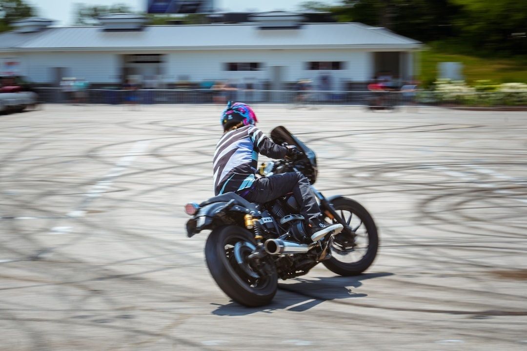 Motorcyclist leaning a sport bike into a turn across a paved lot