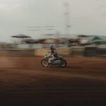 Speedway rider powers a numbered motorcycle across a dirt track
