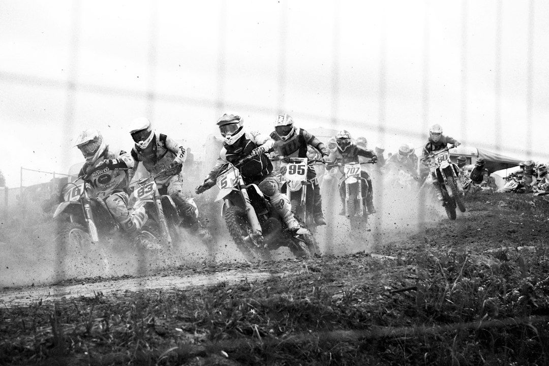 Motocross riders spray dirt while racing across a muddy track